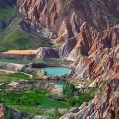 the mountains are covered in green grass and brown rocks, with small lakes surrounded by them