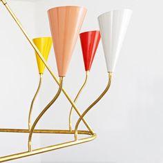 three different colored vases sitting on top of a metal stand in front of a white wall