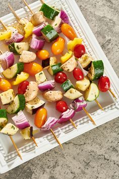 several skewers of vegetables are on a white plate