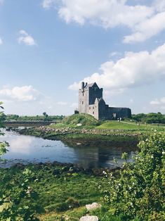 an old castle sitting on top of a lush green field next to a body of water