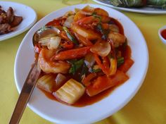 a white plate topped with lots of food on top of a yellow table covered in sauce