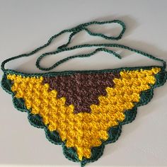 a crocheted bag hanging on a wall next to a white wall with a green string