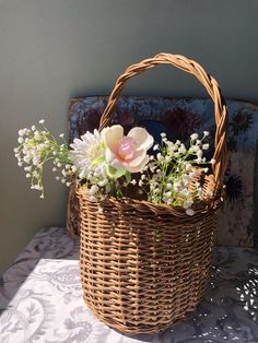 a wicker basket with flowers in it sitting on a white tablecloth next to a blue wall