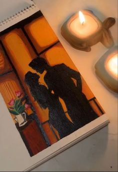 a couple kissing in front of candles on a table next to a notepad and candle holder