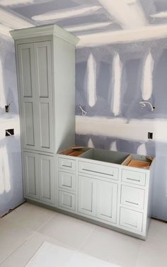 an unfinished kitchen with white cabinets and gray walls