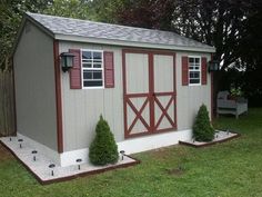 a small shed sitting on top of a lush green field next to a fence and trees