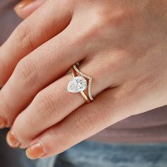 a woman's hand with a diamond ring on top of her finger and an engagement band