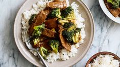 a plate with rice, broccoli and beef on it next to two bowls