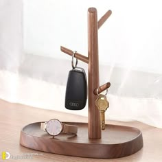 a wooden stand with two keys and a watch on it