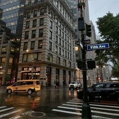 an intersection in the city with cars and people crossing it at night time, on a rainy day