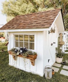 a small white shed sitting on top of a lush green field