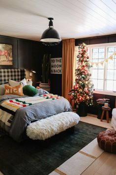 a bed room with a neatly made bed and a christmas tree