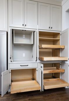 an empty kitchen with white cabinets and wooden shelves