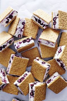 a bunch of cookies with blueberries and cream filling on them sitting on top of a table