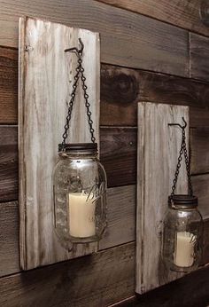 two mason jars are hanging on the wall next to each other with candles in them