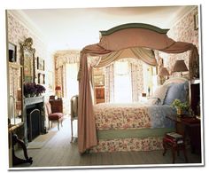 a canopy bed in a bedroom with floral wallpaper