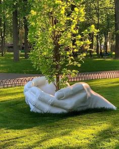 a tree that is sitting in the grass next to a white sculpture on top of green grass