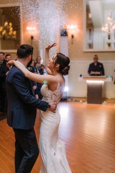 a bride and groom are dancing on the dance floor with confetti falling from their hands