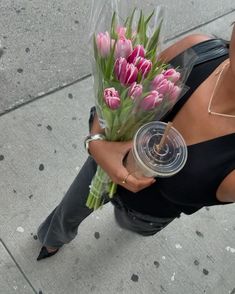 a woman sitting on the sidewalk holding a bouquet of tulips in her hand