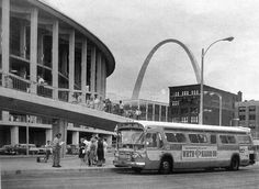 an old bus parked in front of a building with the st louis arch in the background