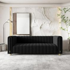 a black couch sitting next to a tall plant in front of a mirror on a wall