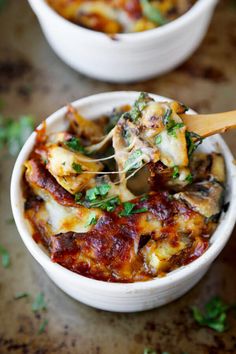 two white bowls filled with lasagna casserole topped with cheese and parsley