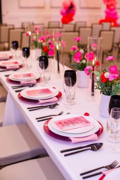 the table is set with pink flowers and place settings