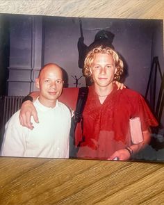 two men standing next to each other on a wooden table