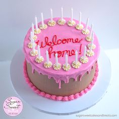 a pink cake with candles and welcome home written on it