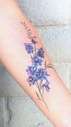 a woman's arm with purple flowers on it and the word love written in cursive writing