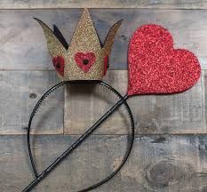 two crowns with hearts on them sitting next to each other in front of a wooden background