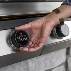 a person turning on an oven with thermometer in front of them and their hand