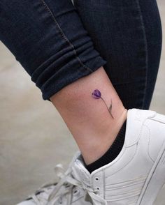 a small purple flower on the ankle is shown in front of a woman's leg