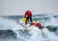 a man riding on the back of a jet ski while being towed by another person