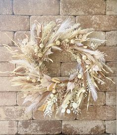 a dried wreath on a brick wall with white flowers and green leaves hanging from it