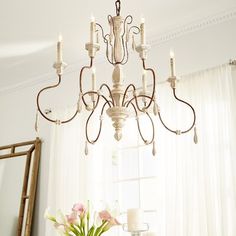 a chandelier hanging from the ceiling in a room with white walls and curtains