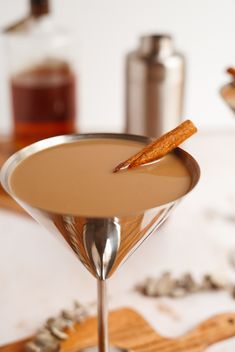 a drink in a martini glass garnished with cinnamon sticks