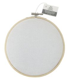 an embroidery kit with a white circle on the front and bottom, hanging from a hook