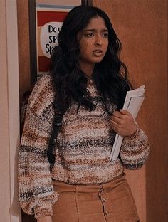 a woman standing in front of a door holding a folder and looking at the camera