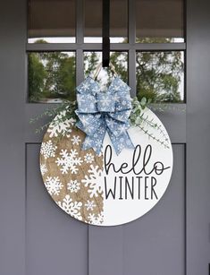 a door hanger that says hello winter with snowflakes and a blue bow