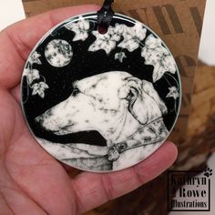 a hand holding a black and white dog ornament with stars in the background