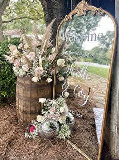 a wooden barrel filled with flowers next to a mirror and sign that says welcome the wedding of ruth & ray