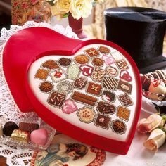 a red heart shaped box filled with lots of different types of candies and chocolates