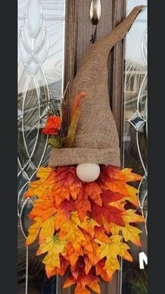 a scarecrow door hanger decorated with fall leaves