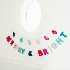 there is a birthday banner hanging on the wall in front of a round window that says happy and bright