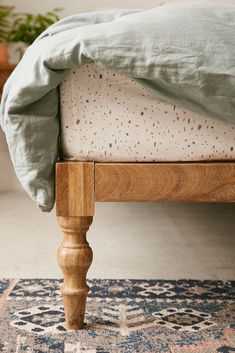 a bed with a wooden headboard and foot board on top of carpeted floor