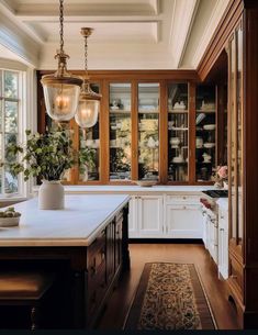 a large kitchen with white cabinets and wood trimming on the ceiling, along with an area rug