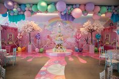 a birthday party with balloons and decorations on the walls, tables and chairs in front of it