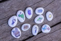 some rocks with pictures on them sitting on a wooden surface