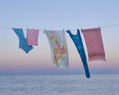 three towels hanging on a clothes line over the ocean